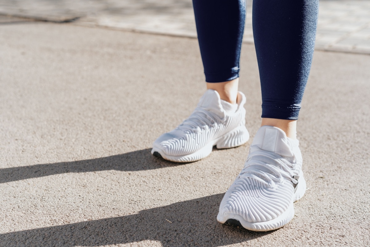 Symbolbild für den Mehrbedarf: Füße und weiße Schuhe, für die das Sozialgericht Hamburg einen Zuschuss zum Bürgergeld wegen krankheitsbedingtem Verschleiß genehmigt hat.