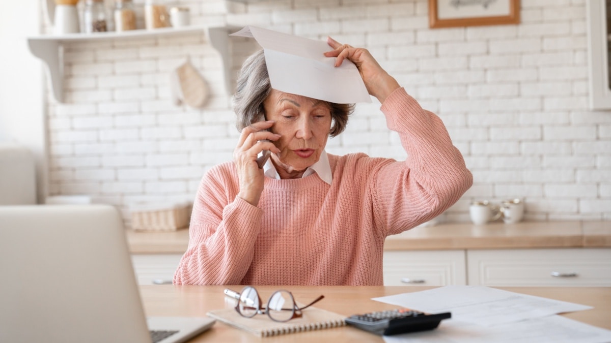 Besorgte Rentnerin am Telefon hält behördliches Schreiben wegen Rente oder Steuern.