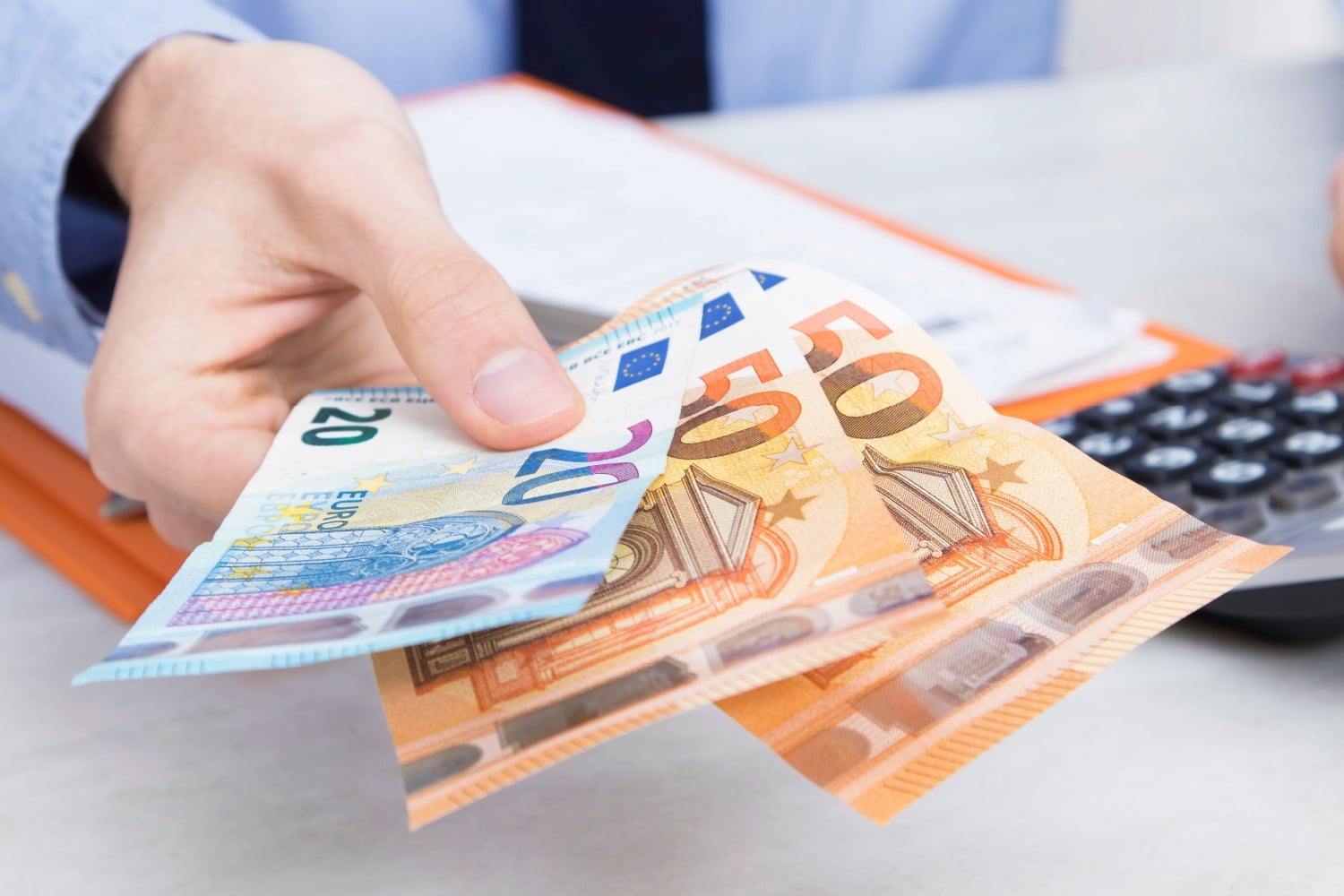 Arbeitgeber hält Geldscheine als Lohn hin, symbolisch für Erwerbseinkommen