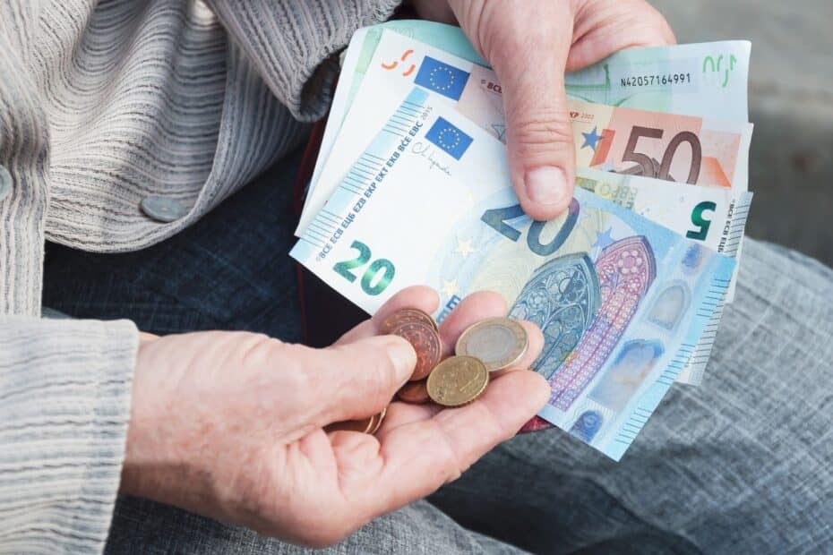 Rentner zählt Euro-Geldscheine und Münzen auf dem Schoß